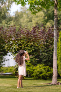 Young girl in pigtails inspecting a tree after Monmouth County tree company service